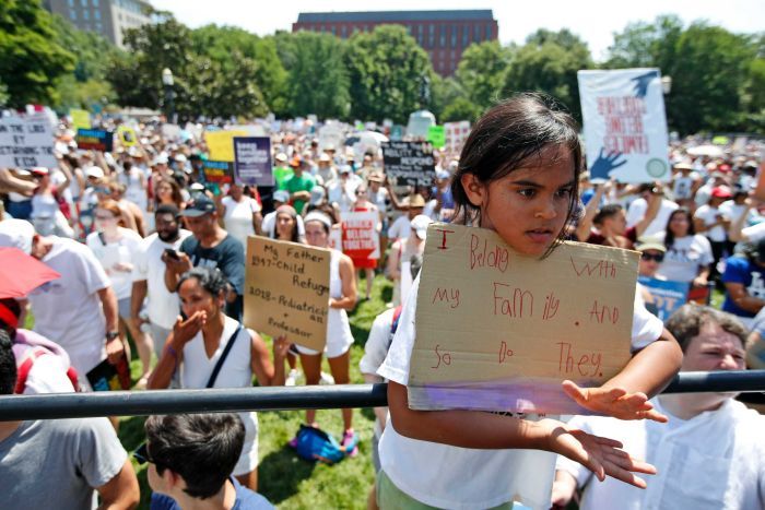 Anti immigration law protests A young girl holds a sign saying 'I belong with my family and so do they.'
