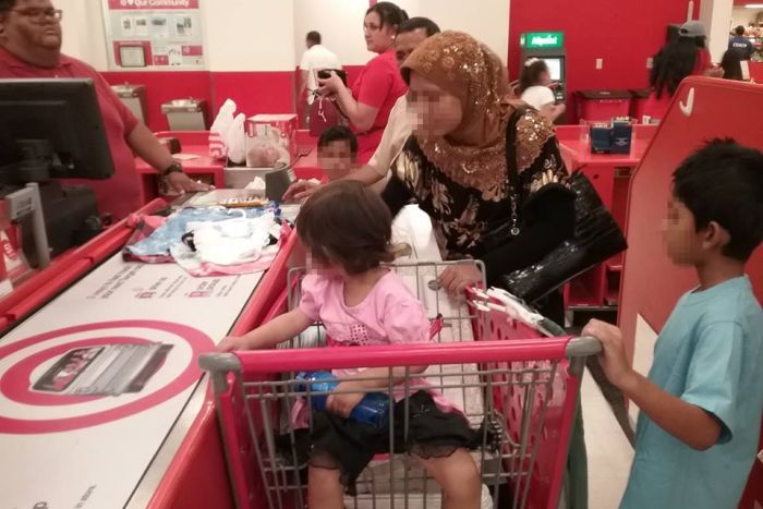 Refugee family resettling in the US A woman with her children at the checkout, purchasing children's clothing  in the US.